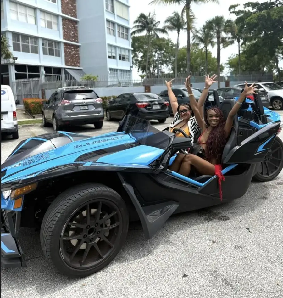 Blue Polaris Slingshot rental Miami Beach โ two friends celebrating